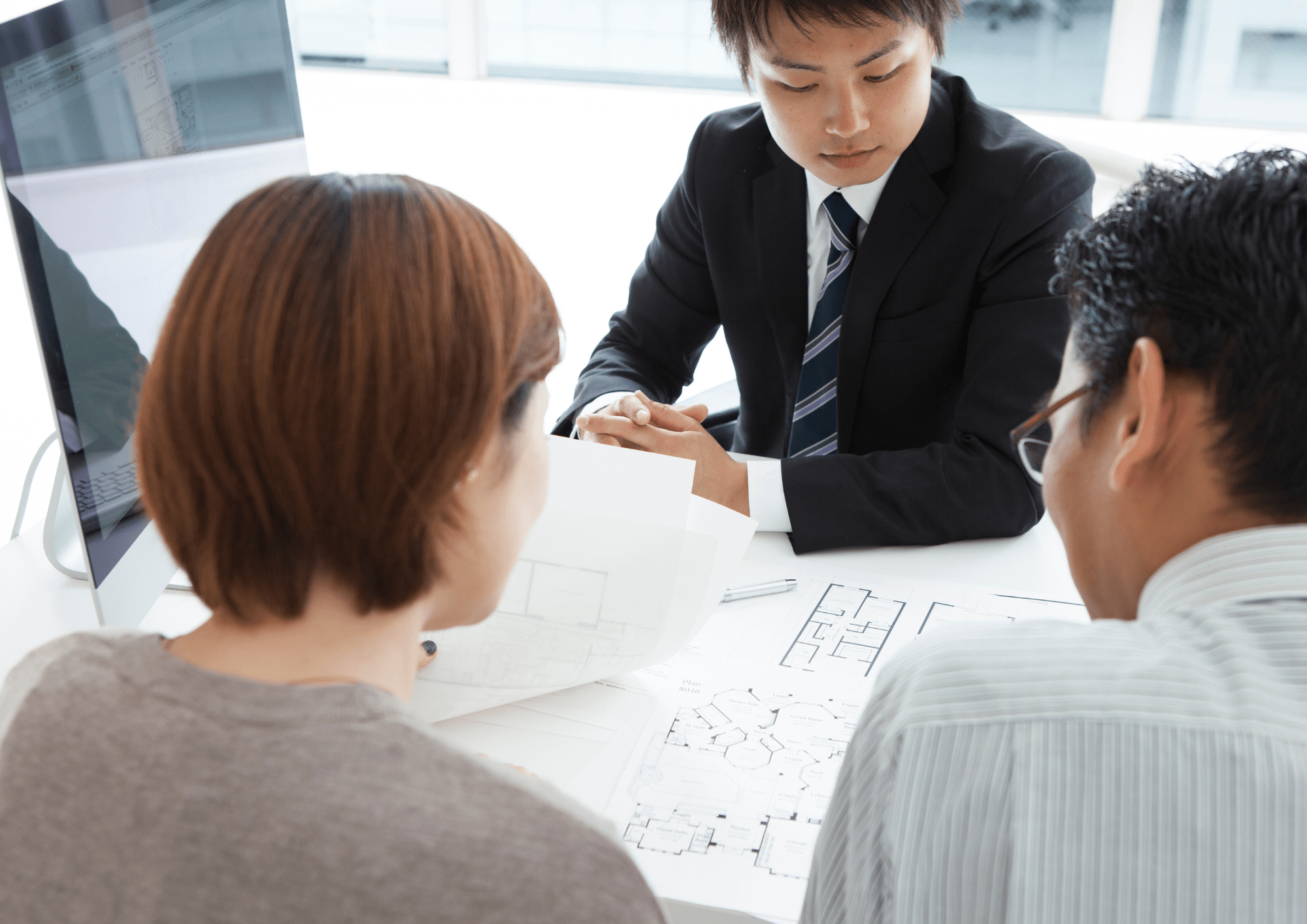 Inmobiliaria mostrando planos explicando diferentes puntos a pareja