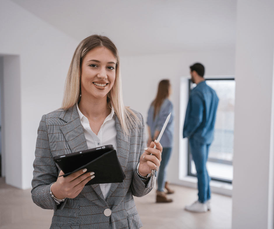 Chica de una inmobiliaria enseñando a una pareja una nueva vivienda