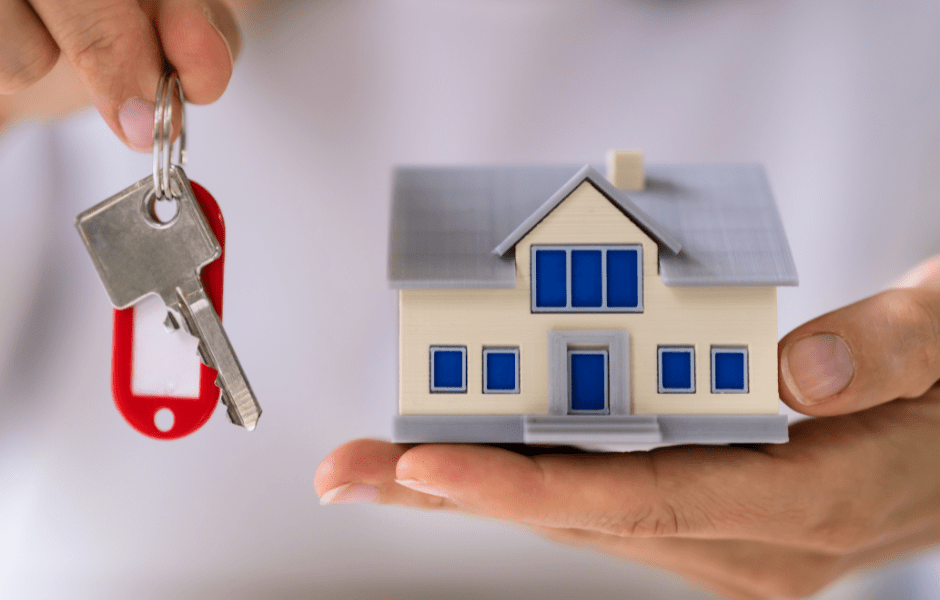 Persona sosteniendo las llaves de una casa y con la otra mano sostiene una casa en forma de maqueta