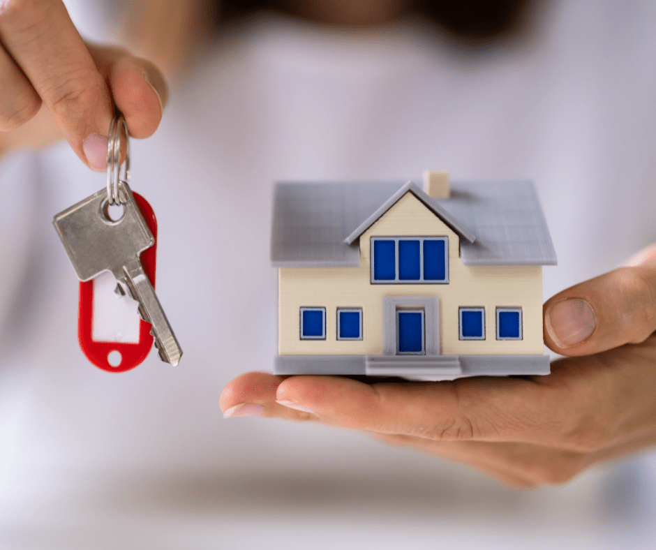 Persona sosteniendo las llaves de una casa y con la otra mano sostiene una casa en forma de maqueta